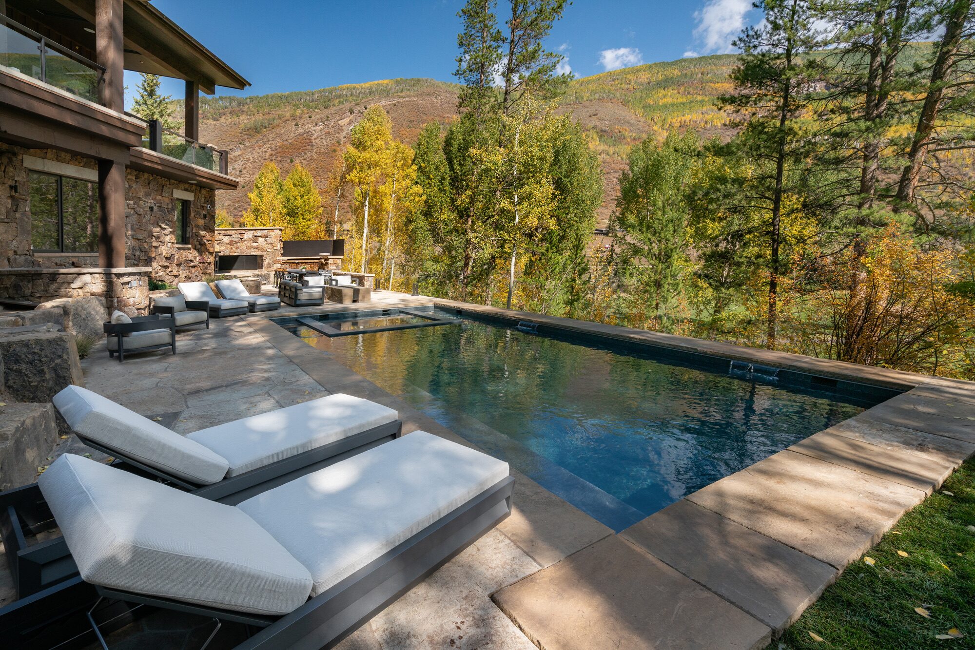 Infinity-edge pool with chaise lounges and Gore Range mountain views